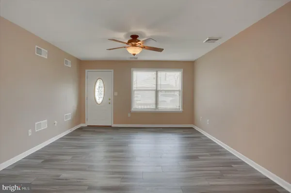 an empty room with wooden floor chandelier fan and windows