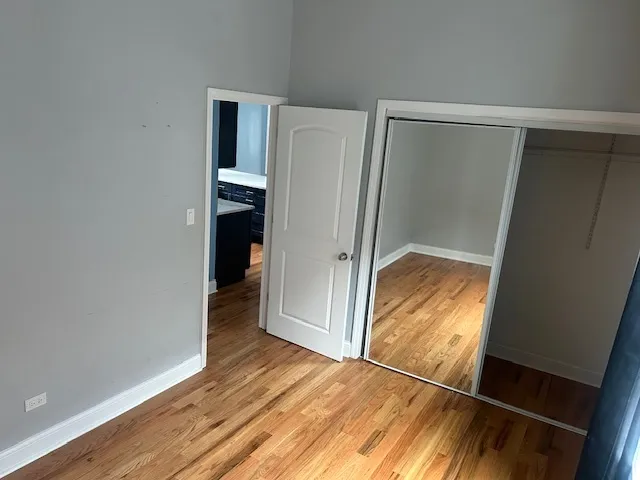 a view of an empty room with wooden floor and closet