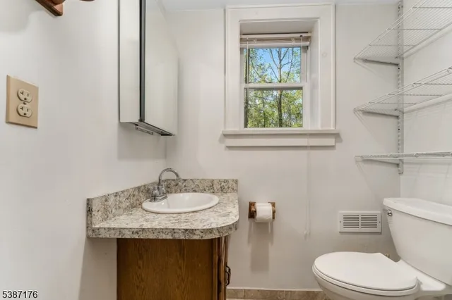 a bathroom with a granite countertop sink a toilet and a window
