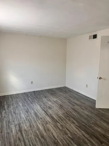 a view of a room with wooden floor and bench in it