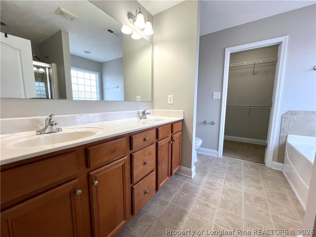 240 Declaration Drive Raeford, NC 28376 - Photo 26 of 37 a spacious bathroom with a double vanity sink a large mirror and a bathtub