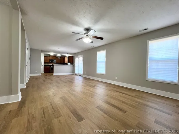 a view of an empty room with window and wooden floor