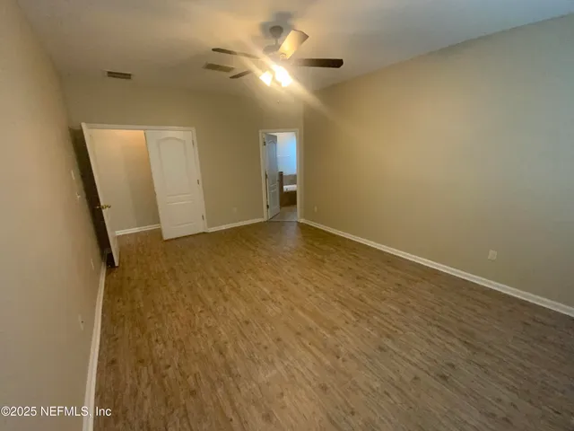 an empty room with wooden floor and a ceiling fan
