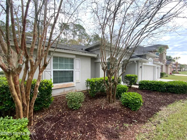 a front view of a house with garden and trees