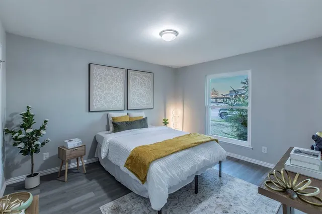 a bedroom with a bed table chair and a window