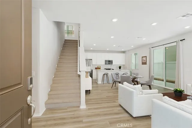 a living room with couches and kitchen view with wooden floor