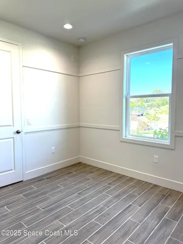 an empty room with wooden floor closet and windows