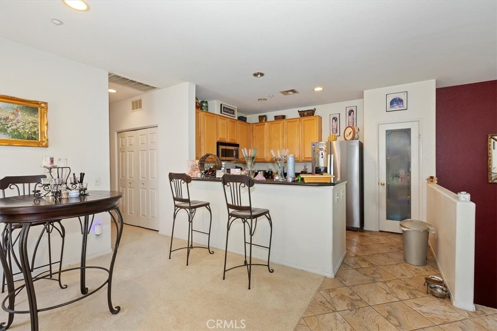 7331 Shelby Place, Unit U140 Rancho Cucamonga, CA 91739 - Photo 11 of 23 a kitchen with stainless steel appliances kitchen island granite countertop dining table chairs and a refrigerator