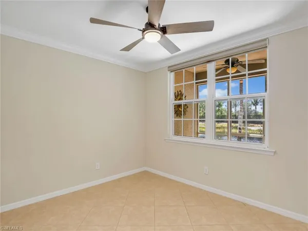 an empty room with chandelier fan and windows