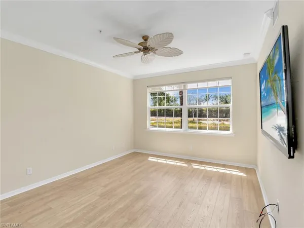 an empty room with wooden floor and ceiling fan