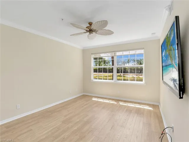 an empty room with wooden floor and ceiling fan
