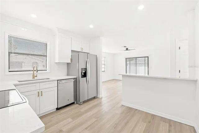 a kitchen with white cabinets and wooden floor