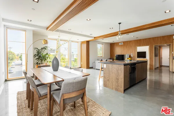 a kitchen with stainless steel appliances kitchen island granite countertop a table chairs sink and wooden cabinets