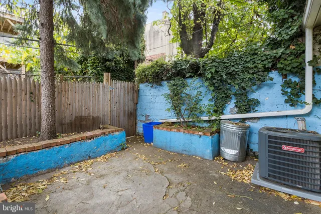 a view of a backyard with large trees and wooden fence