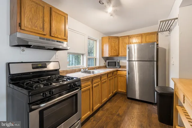 a kitchen with granite countertop a refrigerator stove and wooden floor
