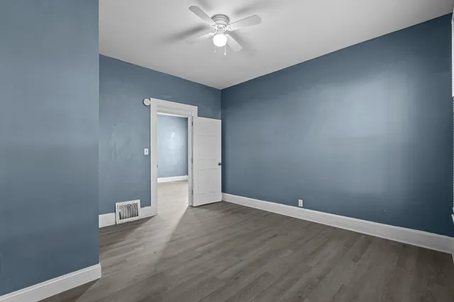 an empty room with wooden floor and a ceiling fan