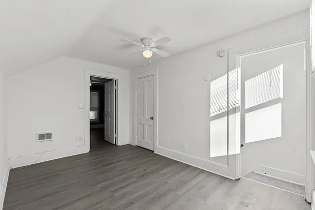an empty room with wooden floor and windows