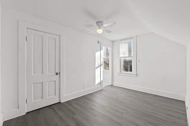 a view of an empty room with a window and wooden floor