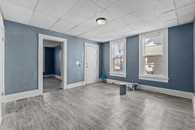a view of an empty room with a window and wooden floor