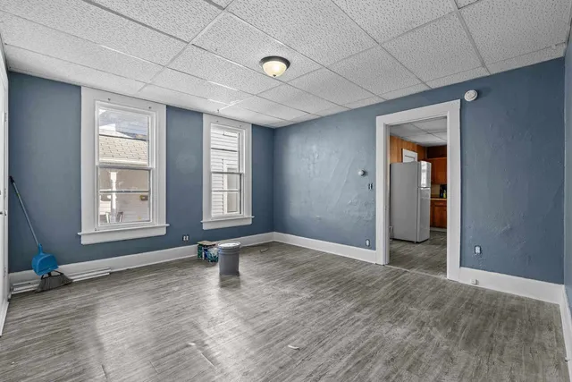 a view of an empty room with window and wooden floor