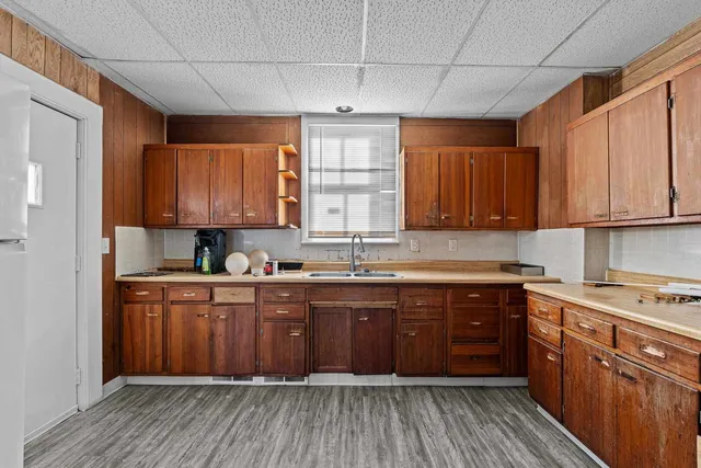 a kitchen with a refrigerator a sink dishwasher a stove and white cabinets with wooden floor