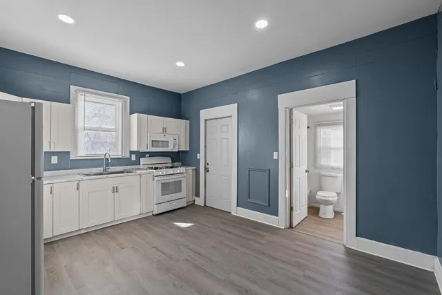 a large kitchen with a refrigerator a stove top oven a sink and dishwasher with wooden floor