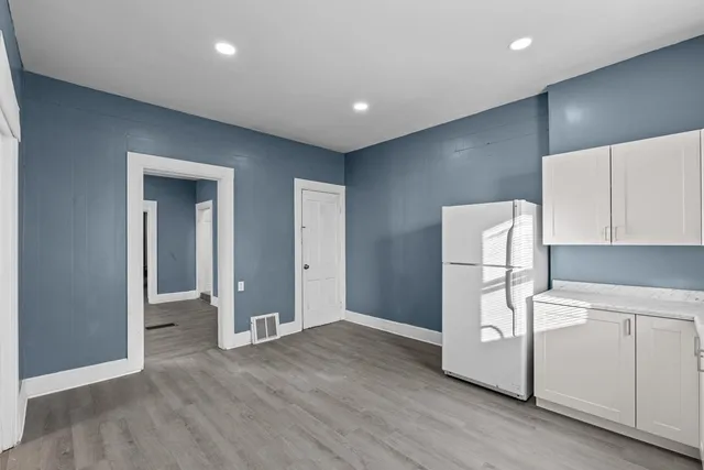 a view of a kitchen with a fridge and wooden floor