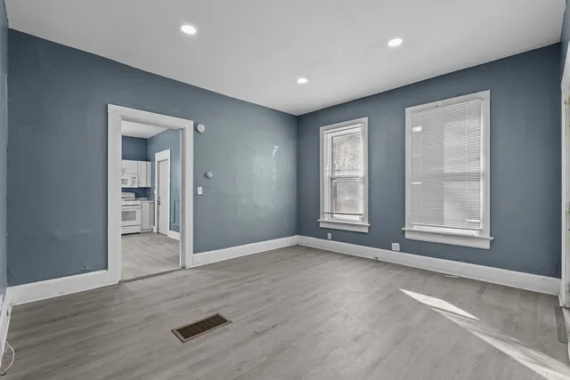 an empty room with wooden floor and windows