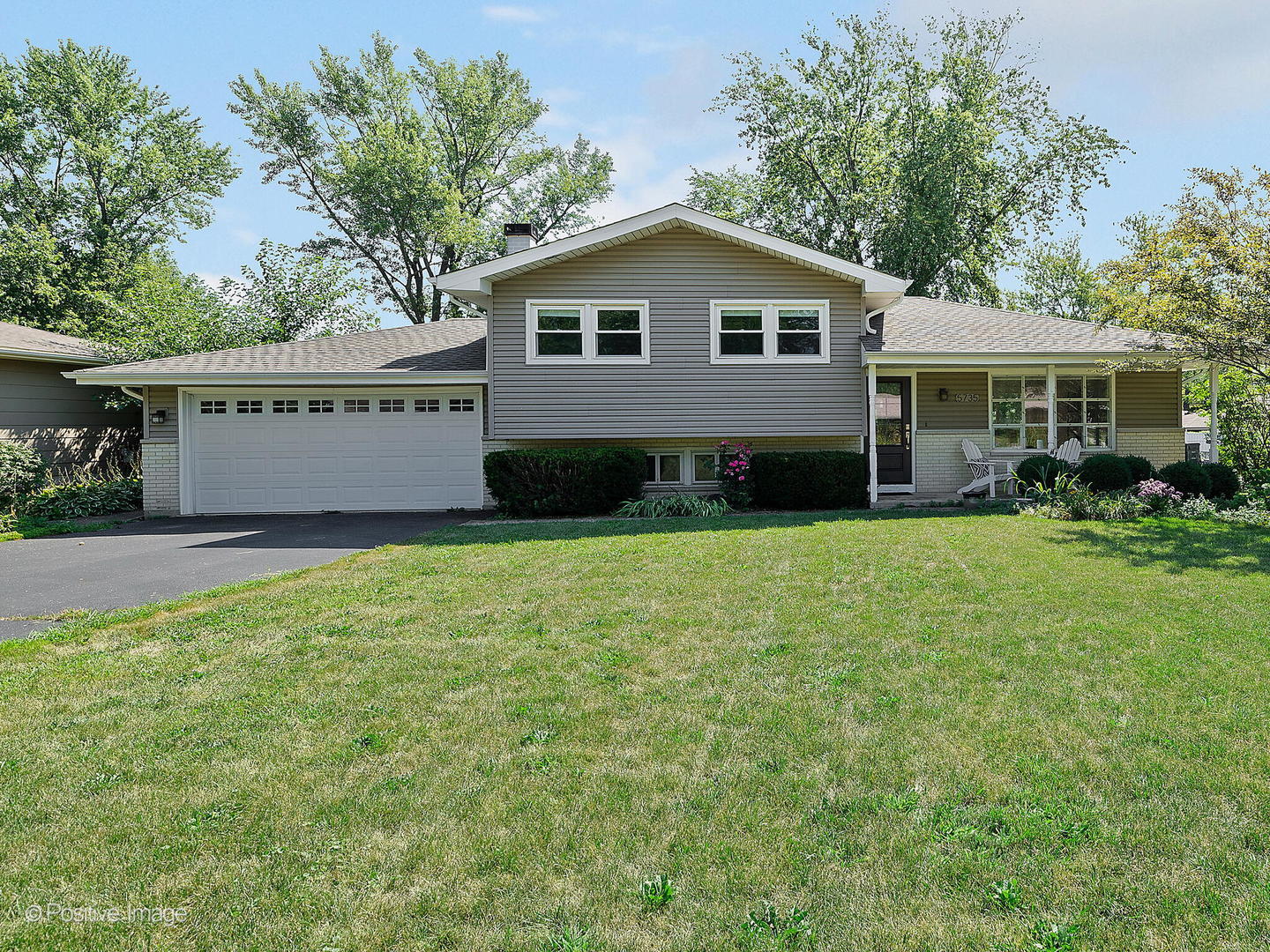 a front view of a house with a garden and trees
