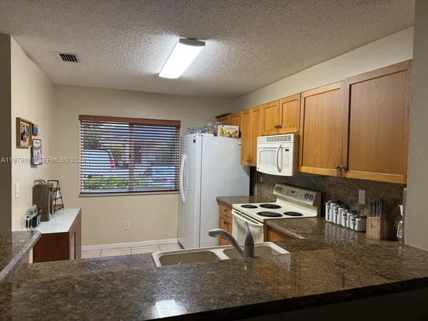 a kitchen with granite countertop a stove a sink and a microwave