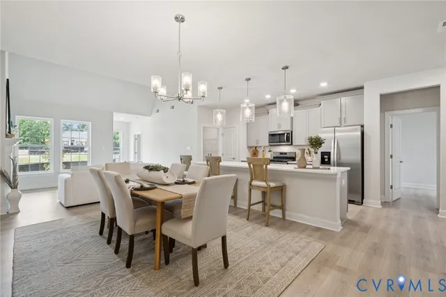 a view of a dining room and livingroom with furniture a rug a fireplace and a chandelier