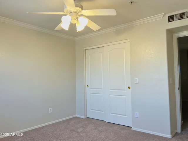an empty room with a chandelier fan and closet