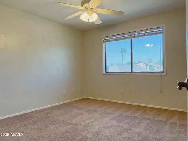 an empty room with a window and a fan