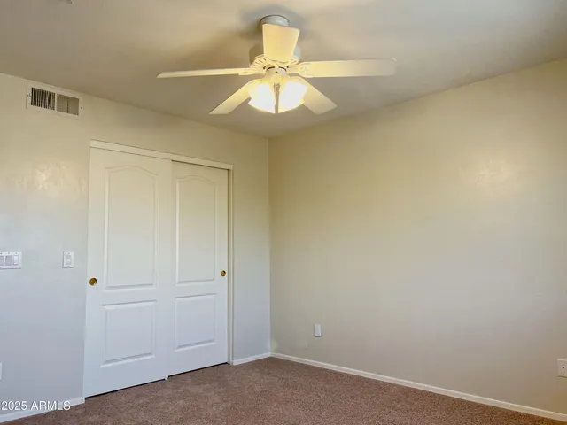 an empty room with a chandelier fan and closet