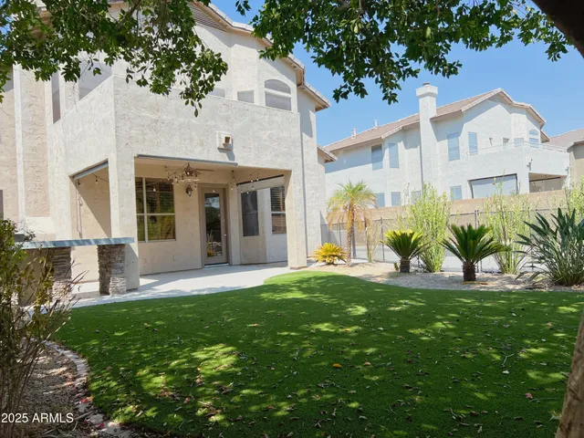 a view of a white house with a big yard and potted plants