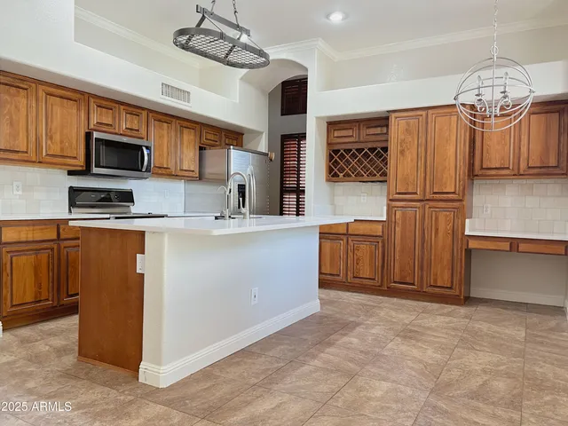 a kitchen with stainless steel appliances granite countertop a sink a stove a refrigerator cabinets and chairs