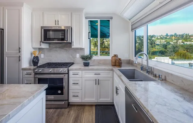 a kitchen with granite countertop a stove a sink and a microwave
