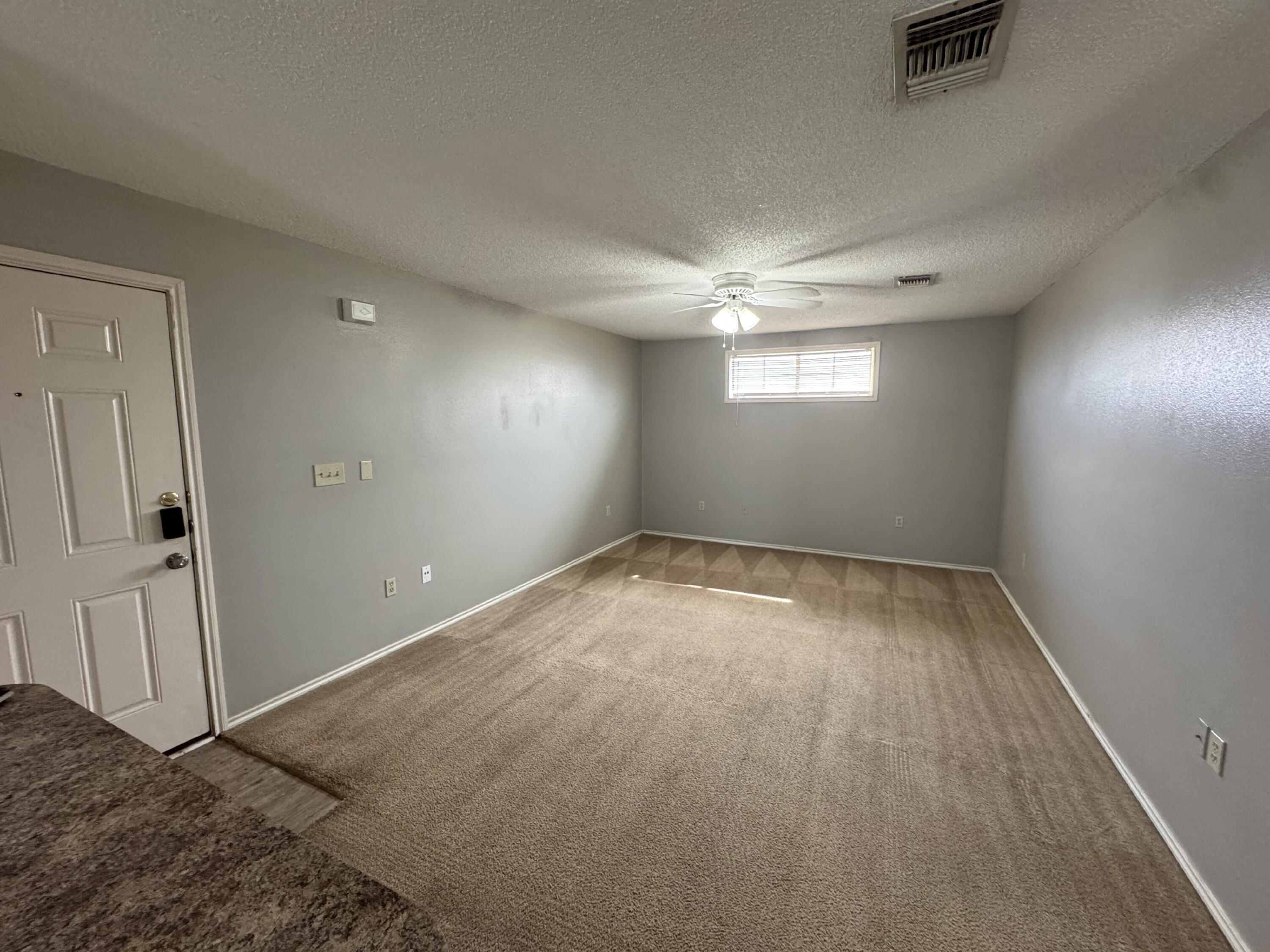 5839 7th Street, Unit D Lubbock, TX 79416 - Photo 2 of 9 an empty room with windows and fan