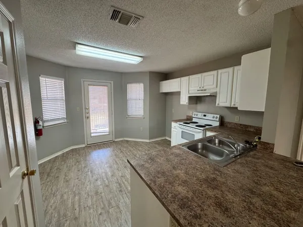 a kitchen with granite countertop a stove a sink dishwasher and a refrigerator