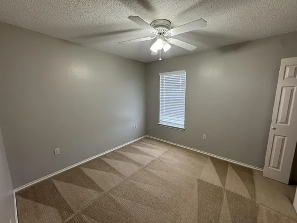 an empty room with windows and fan