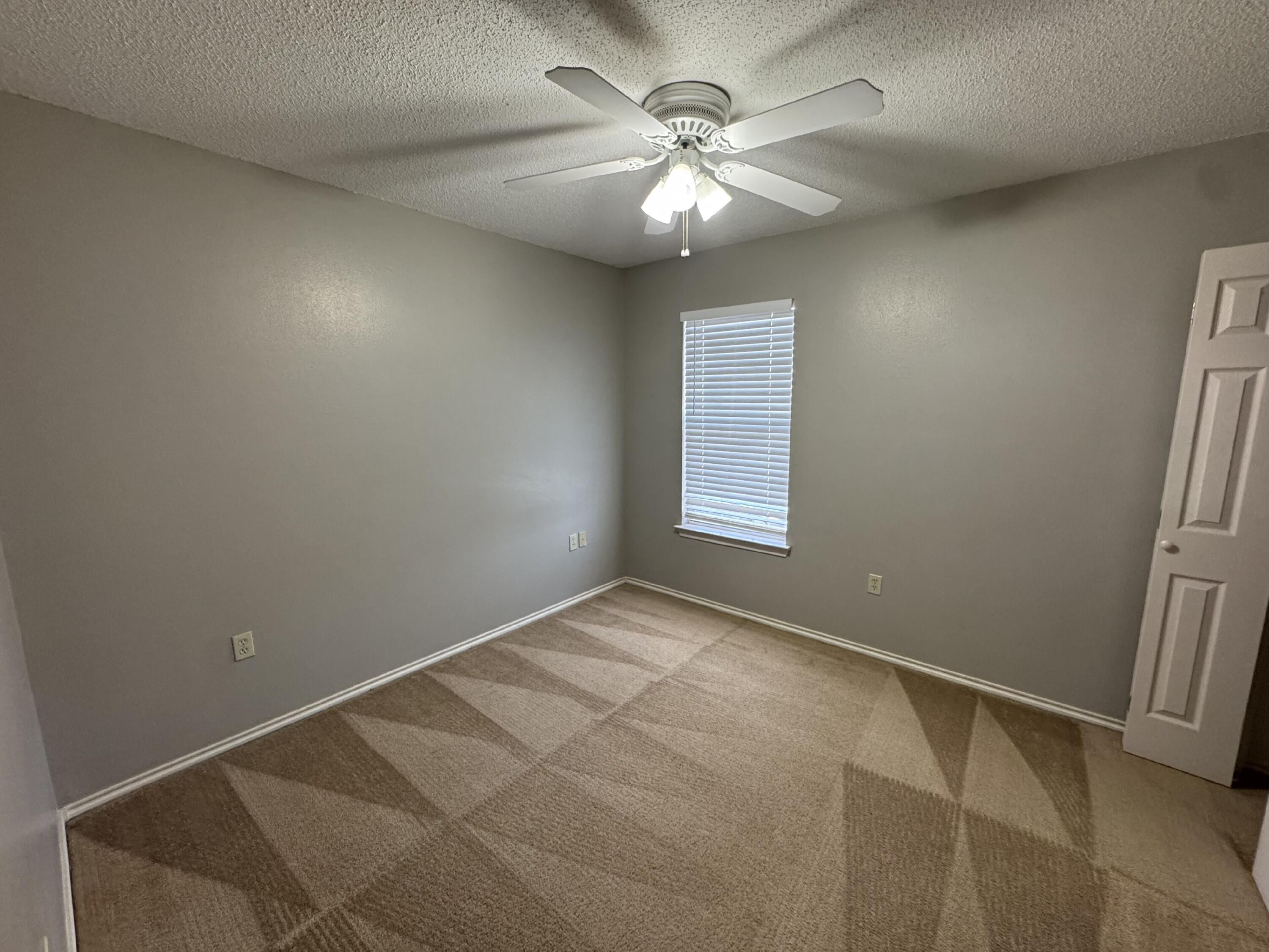 5839 7th Street, Unit D Lubbock, TX 79416 - Photo 7 of 9 an empty room with windows and fan