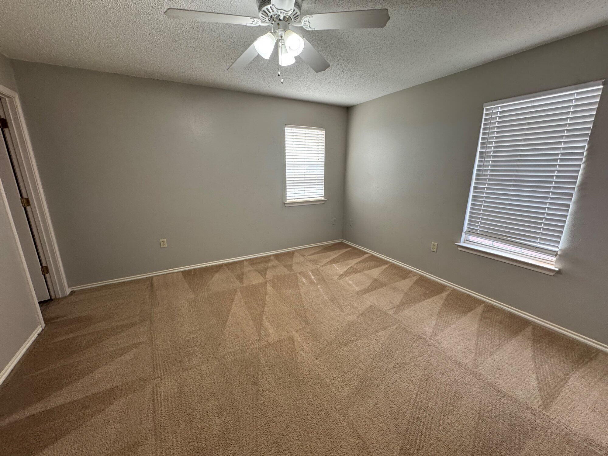 5839 7th Street, Unit D Lubbock, TX 79416 - Photo 8 of 9 an empty room with windows and fan