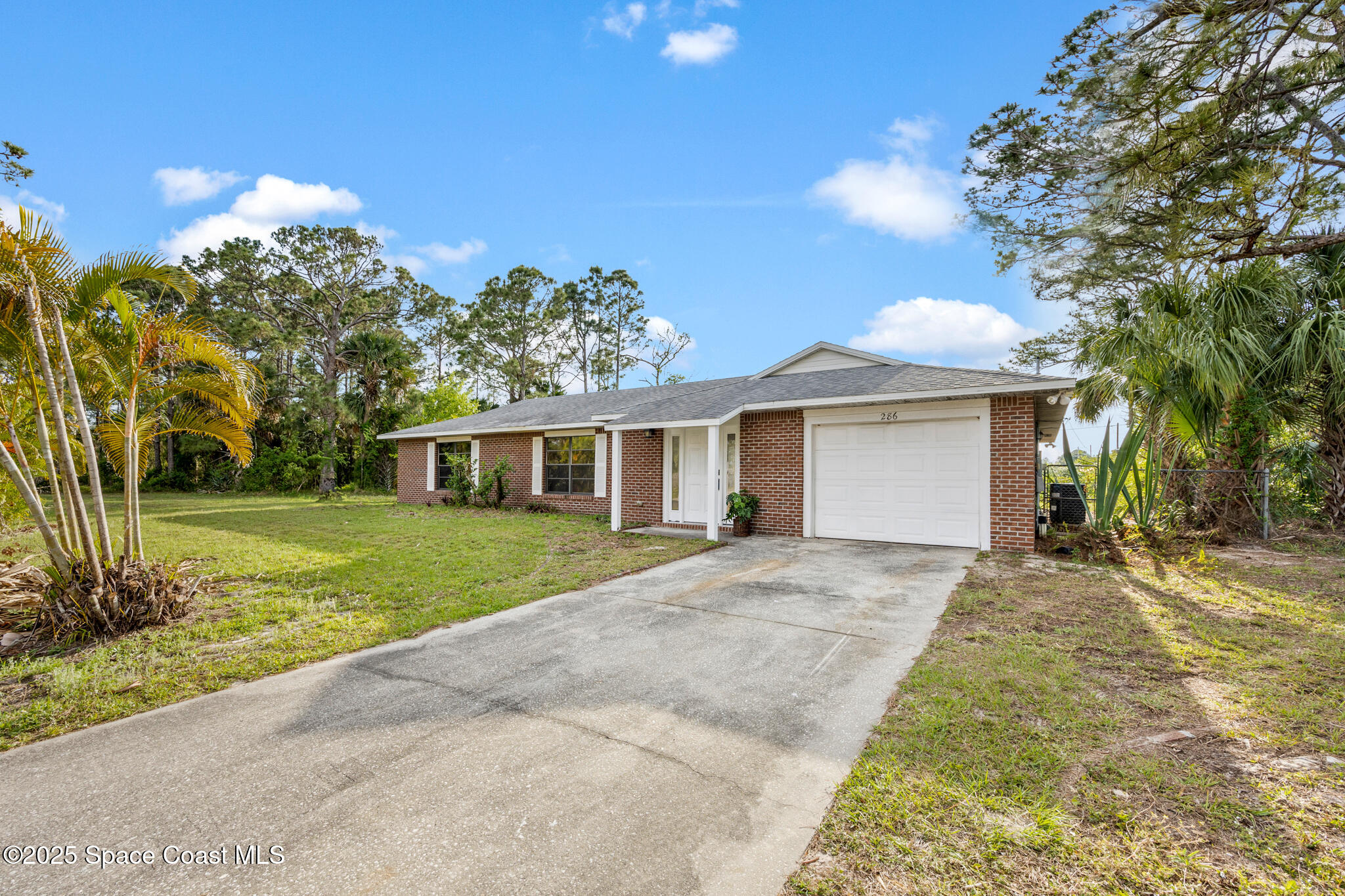 286 Alegriano Road Northwest Palm Bay, FL 32907 - Photo 1 of 24 a front view of a house with a garden and trees