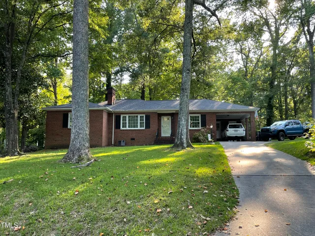 a front view of a house with a garden and trees