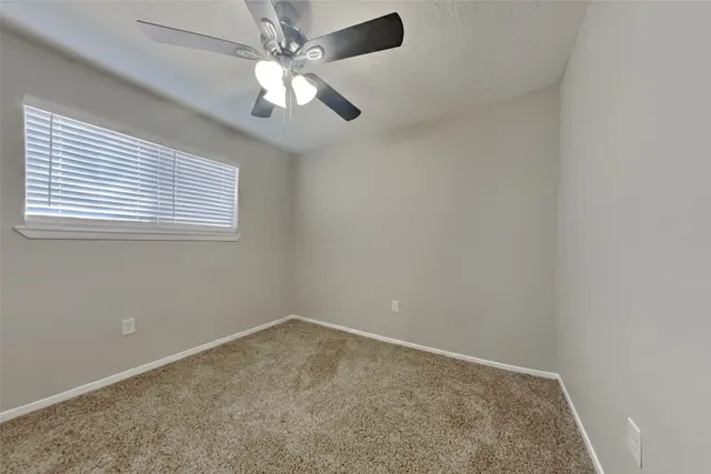 an empty room with a chandelier fan and windows