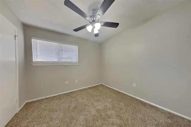 an empty room with a chandelier fan and windows