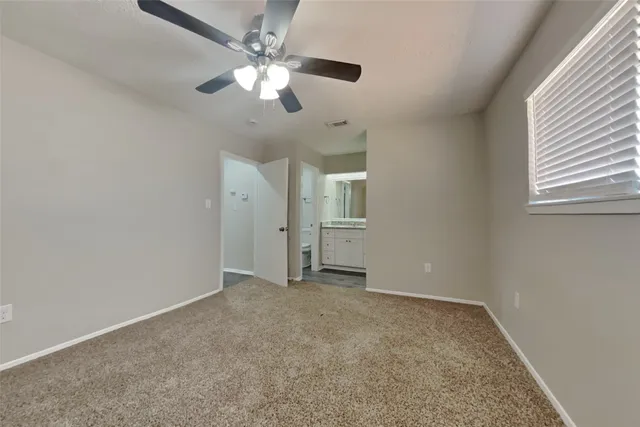 an empty room with chandelier fan and windows