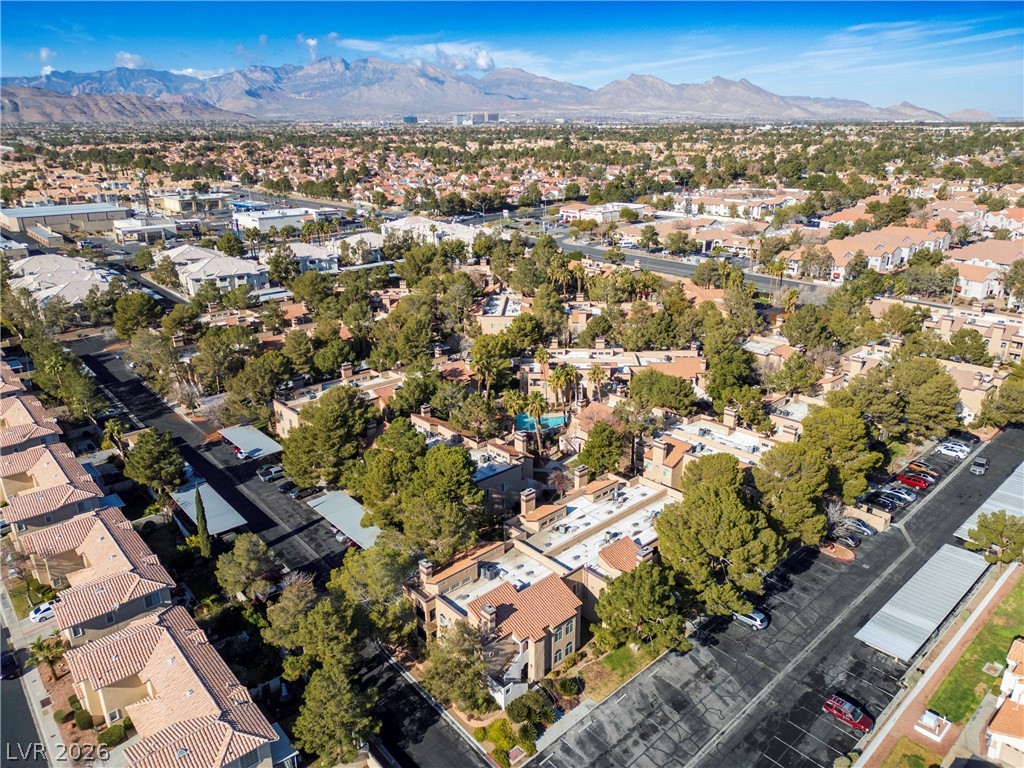 9325 West Desert Inn Road, Unit 260 Las Vegas, NV 89117 - Photo 4 of 4 An aerial perspective reveals a vibrant community with abundant trees, a shimmering pool, and majestic mountains in the distance.