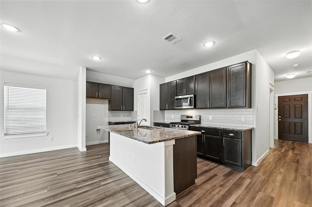 5019 Flanagan Drive Forney, TX 75126 - Photo 5 of 19 a kitchen with stainless steel appliances granite countertop a stove top oven a sink dishwasher and a refrigerator with wooden floor