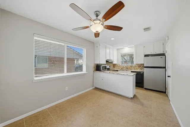 a kitchen with a refrigerator and white cabinets